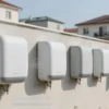 A modern residential courtyard in Protvino with a row of sleek, contemporary towel dryers mounted on a light-colored wall, some dryers showing water droplets or steam indicating usage, a few people hanging towels on them, background showing typical Russian low-rise buildings and a clear blue sky, clean and bright daylight, no text or letters visible