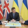 A high-quality image depicting a meeting between British and Ukrainian officials discussing military technology. The scene should include a table with documents and a map of Ukraine, with both parties engaged in serious conversation. The background should suggest a secure, diplomatic setting with subtle British and Ukrainian flags in the room.