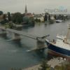 A dramatic scene showing a symbolic weak point in Europe's infrastructure, such as a cracked or damaged bridge or dam, with subtle references to maritime themes like a damaged ship or anchor, set in a realistic European landscape with muted colors and a tense atmosphere