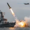 A military scene depicting the Northern Fleet launching a missile strike against a fortified enemy position. Show a missile being fired from a naval platform, with visible smoke trails and explosions in the distance. Include military ships, aircraft, and ground forces in the background. Use realistic military equipment and a dramatic, action-oriented composition.