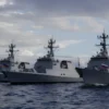 A realistic photograph of modern Russian naval warships anchored in the Baltic Sea, showing detailed hulls, flags, and maritime environment with natural lighting and water reflections