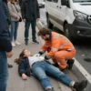 A solemn scene showing a woman lying on a paved sidewalk after being struck by a minibus, with emergency responders attending to her, bystanders looking on with concern, and a damaged minibus nearby, realistic depiction of a tragic traffic accident aftermath